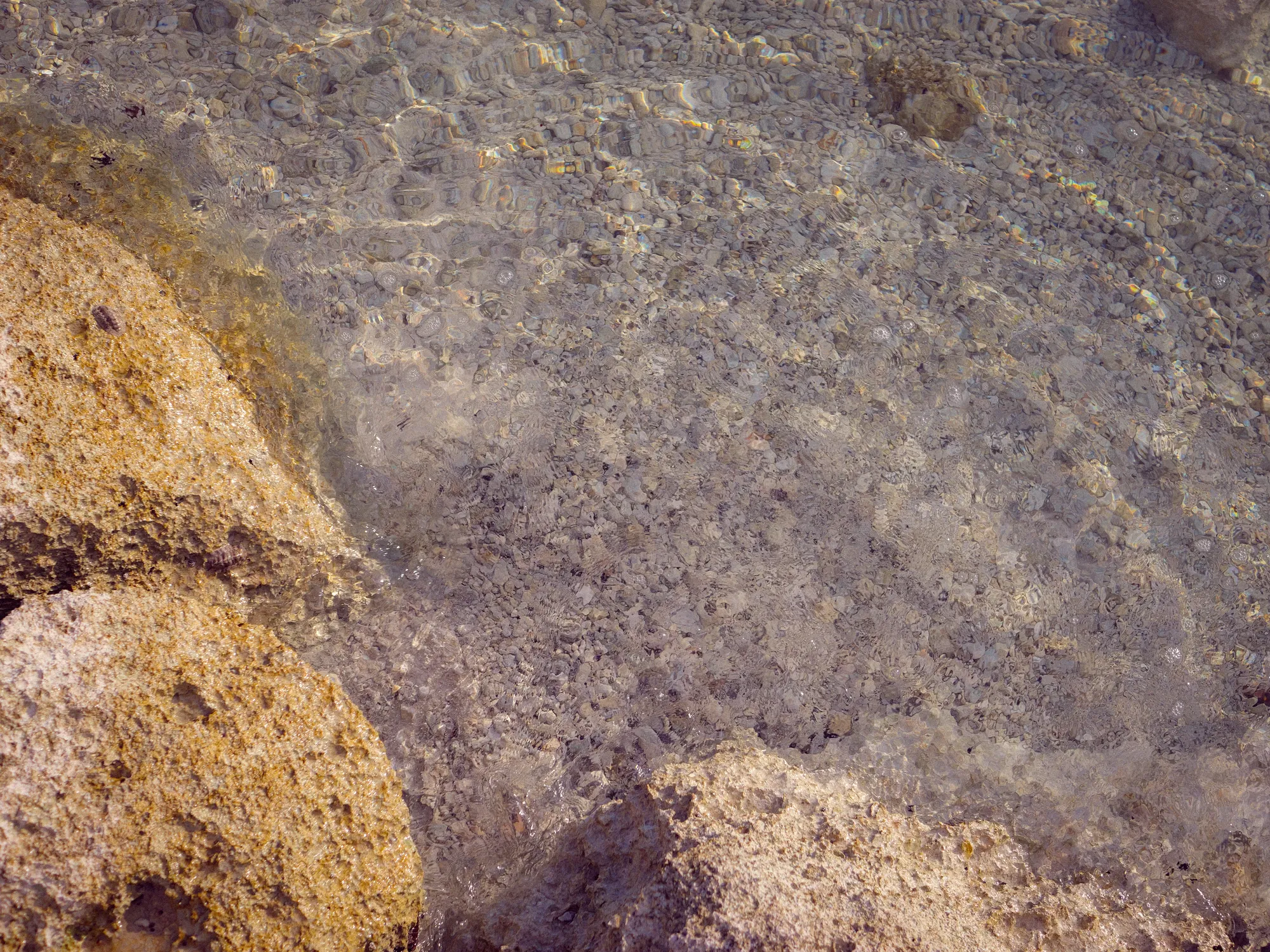 Clear shallow water over pale rock