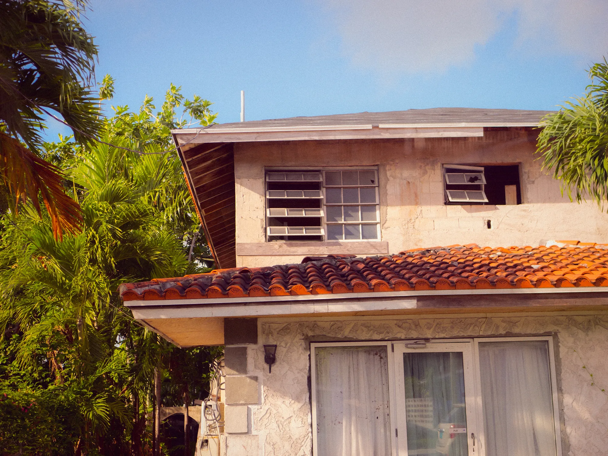 A stone house with a terracotta roof among palms