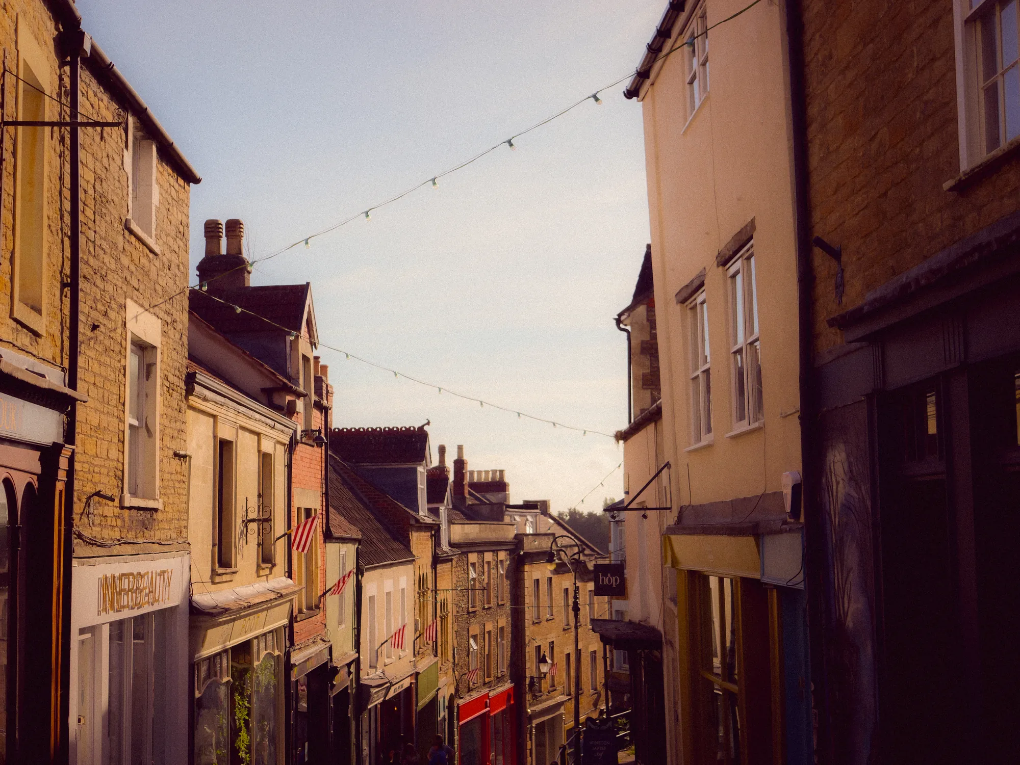 A narrow street of stone shopfronts under strings of bunting