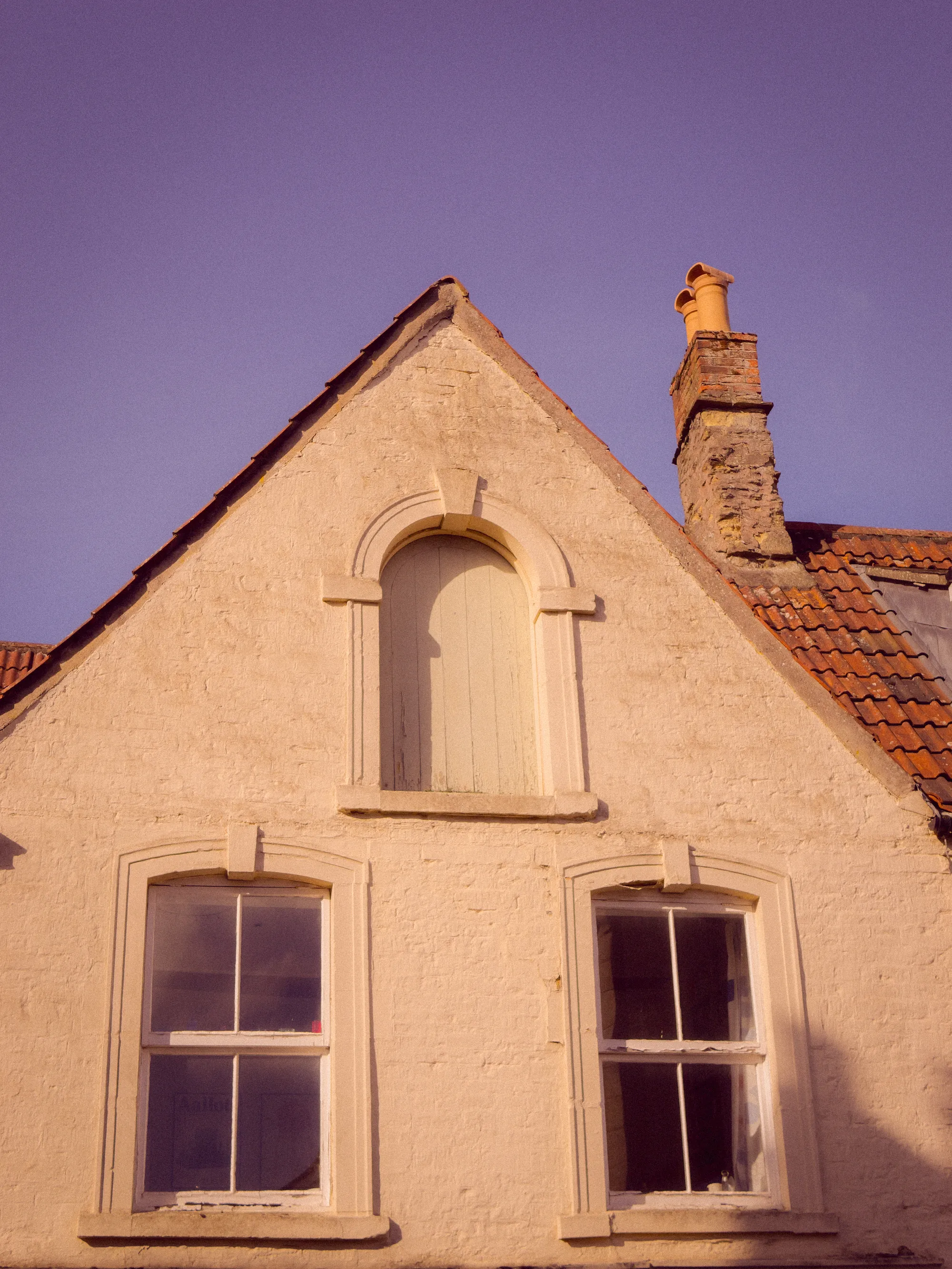 A gable end with an arched window and a chimney